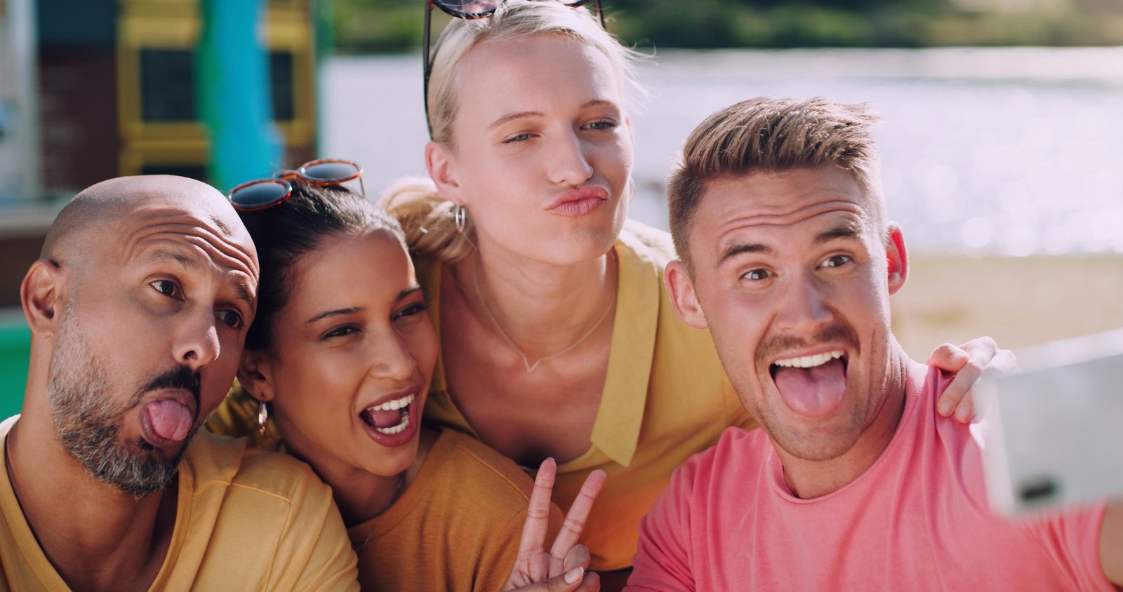 Four friends making playful faces for an outdoor selfie